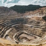Aerial view of a large open-pit mine with terraced excavation during summer.