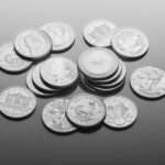 A close-up of various silver bullion coins, showcasing intricate designs on a reflective surface.